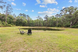 A pond with two chairs and a table in a grassy area surrounded by trees. - The Low Country Loft- Comfy 1BDRM Loft-4 Pass Golf Cart Included (Daufuskie Island)
