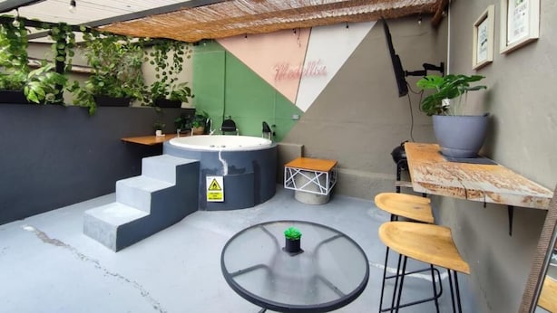 A patio area with a hot tub, outdoor seating, and a staircase leading to an upper level. - Libertador Aptos l Jacuzzi l In Provenza (Medellín)