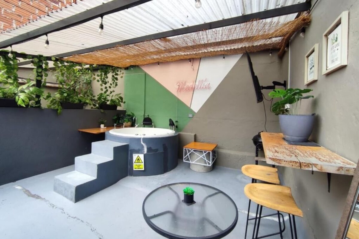 Ein Patio mit Whirlpool, Sitzgelegenheiten im Freien und einer Treppe zu einer oberen Ebene.