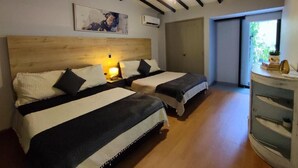 A bedroom with two beds, a ceiling fan, a wooden headboard, a bedside table with a lamp, and a window with a view. - Libertador Aptos l Jacuzzi l In Provenza (Medellín)