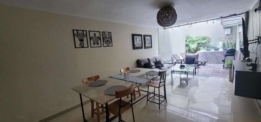 Un área de comedor con una mesa y sillas, un sofá y un televisor.