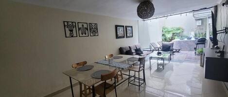 Un área de comedor con una mesa y sillas, un sofá y un televisor.