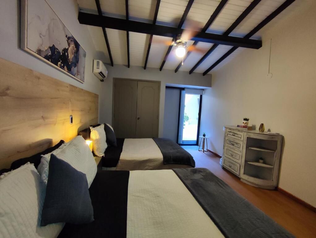 A bedroom with two beds, a ceiling fan, a dresser, and a window.