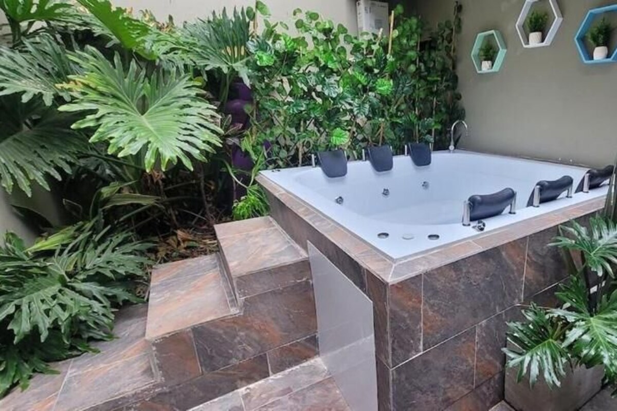 Ein Wellnessbereich mit Whirlpool, umgeben von Topfpflanzen und einer Steinsäule.