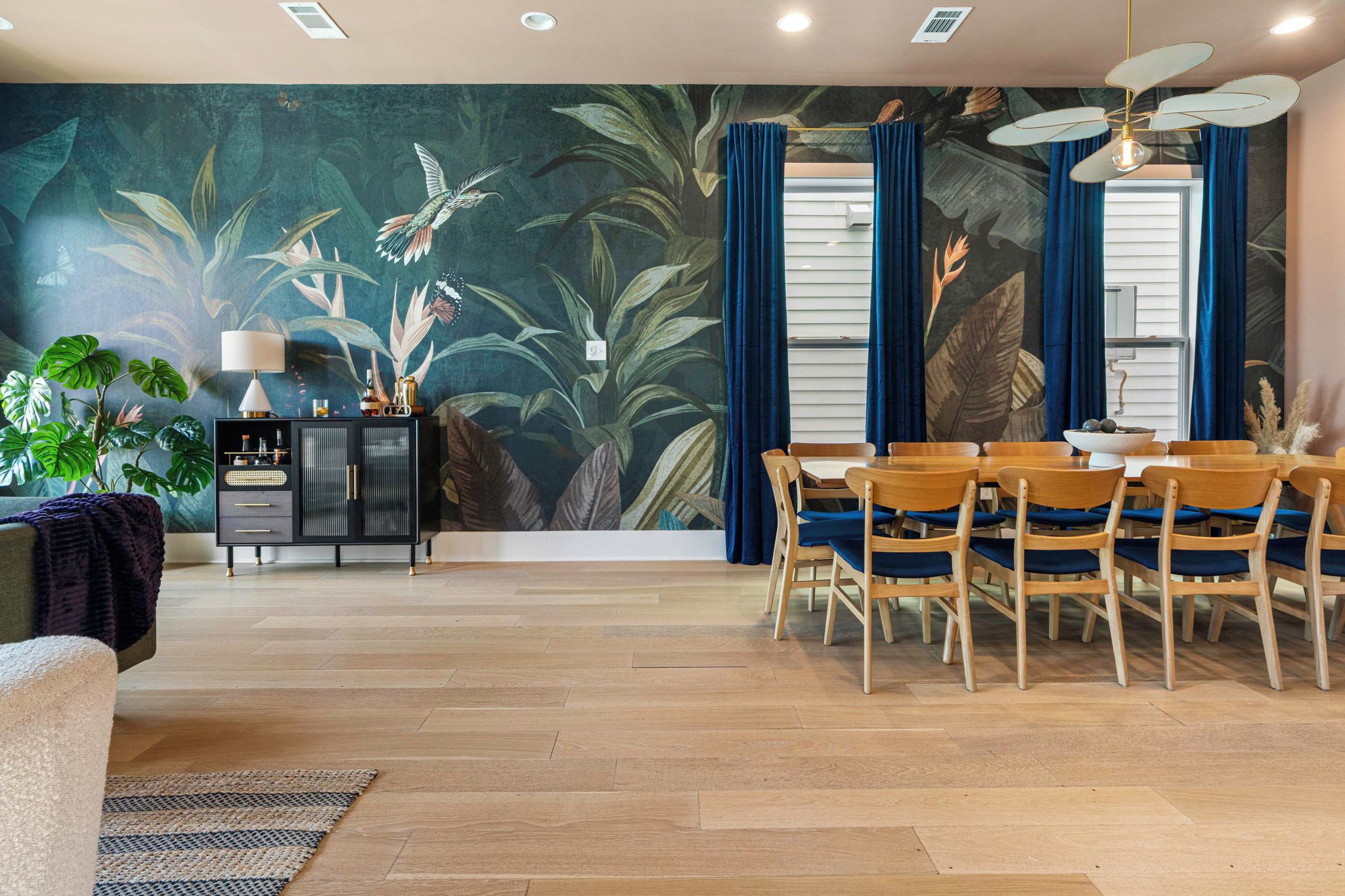 A dining area with a table set for four, surrounded by wooden chairs with blue cushions.