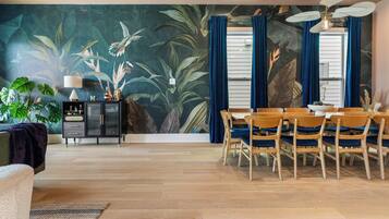 A dining area with a table set for four, surrounded by wooden chairs with blue cushions.