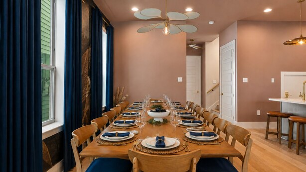 A dining room with a long wooden table set for a meal, wooden chairs, and a ceiling fan.
