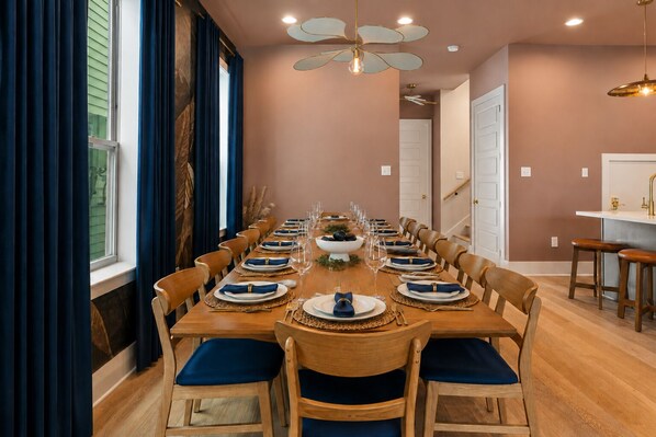 A dining room with a long wooden table set for a meal, wooden chairs, and a ceiling fan.