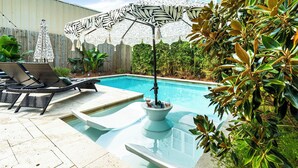 A swimming pool with lounge chairs and a decorative umbrella.