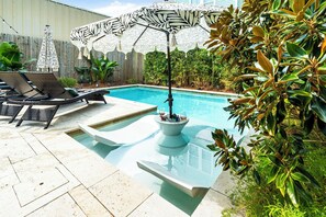 A swimming pool with lounge chairs and a decorative umbrella.