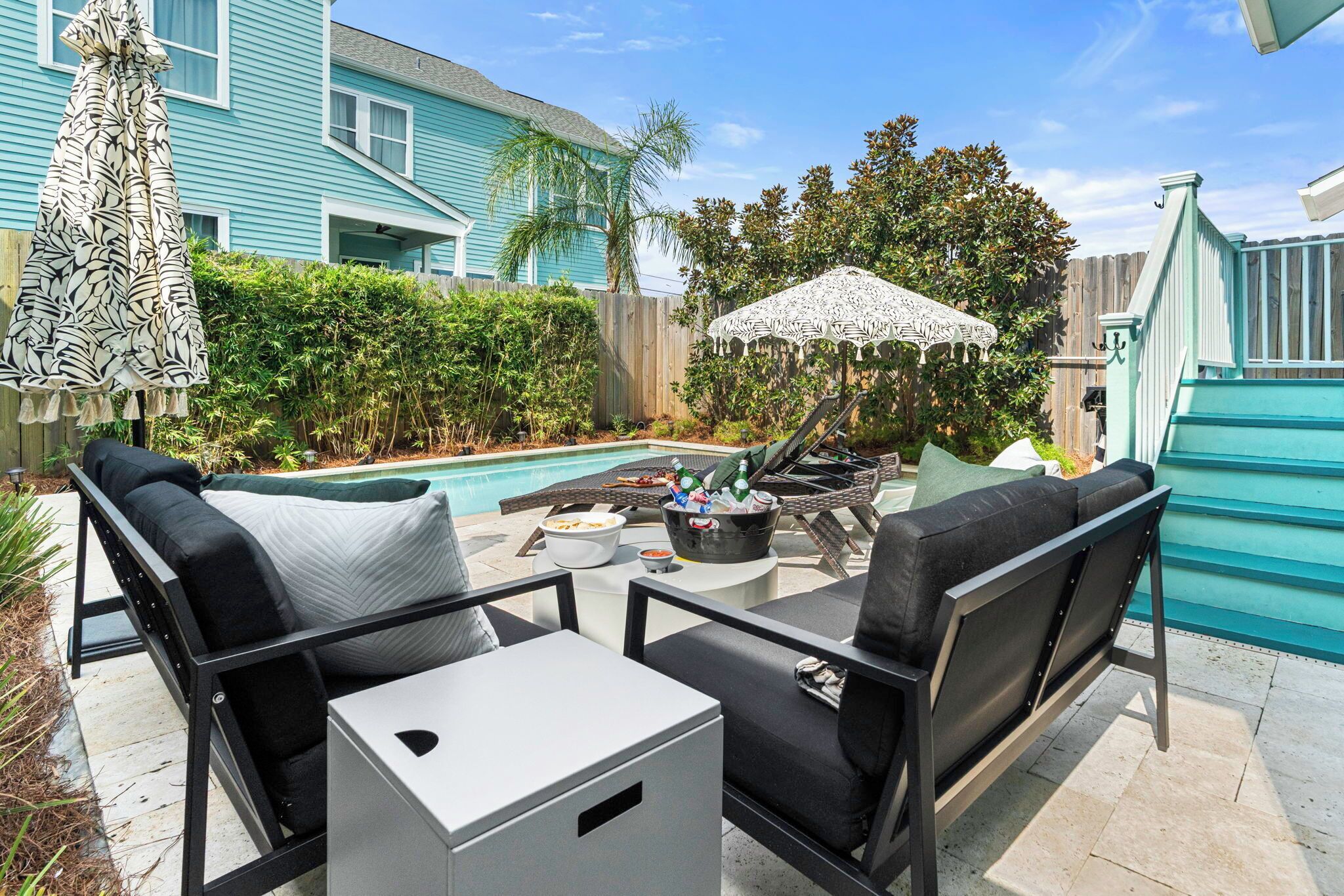 A backyard with a pool, outdoor furniture, and a patio umbrella.