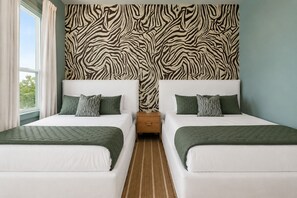 A double room with two beds, a zebra-patterned headboard, and a window with curtains. - Maison de Toulouse | Moody | Heated Pool • Near FQ (New Orleans)