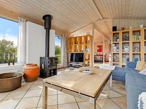 Een gezellige woonkamer met een open haard, een televisie, een boekenkast en een eethoek.
