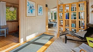 Ett rymligt rum med träpanel på väggarna, en bokhylla, en fåtölj och en matplats.