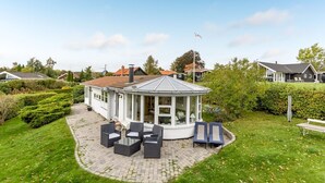 Ett hus med ett vinterträdgård, utomhusmöbler och en välskött trädgård.