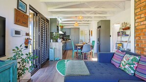 Un salon chaleureux avec un canapé bleu, un coin repas avec des chaises, une cuisine avec un comptoir et un mur en briques.