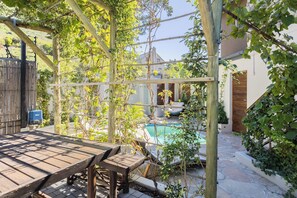 A wooden pergola with climbing plants, a stone pool, and a patio table. - New Mountain Retreat with Scenic Views (Cape Town)
