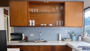 Une cuisine avec des meubles en bois, une cuisinière à gaz, un évier et une fenêtre donnant sur un paysage urbain.