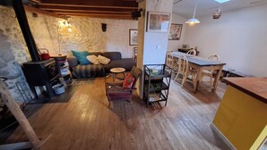 A cozy living area with a fireplace, wooden furniture, and a stone wall.