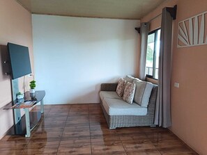 A living room with a sofa, a TV, a small table with a plant, and a window with curtains. - Apartment in La Fortuna 2 min from the park (La Fortuna)
