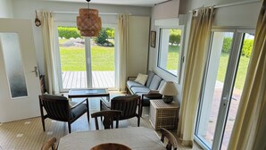 A dining area with a large wooden table, chairs, a sofa, and a lamp. - Les Lutins - Family home - Private beach access (Concarneau)