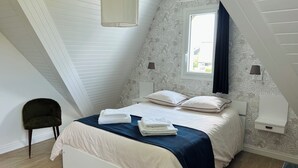 A bedroom with a bed, pillows, a nightstand, a lamp, a chair, and a window. - Les Lutins - Family home - Private beach access (Concarneau)