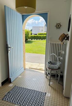 A blue door leading to a tiled entrance area with a white chair and a basket. - Les Lutins - Family home - Private beach access (Concarneau)