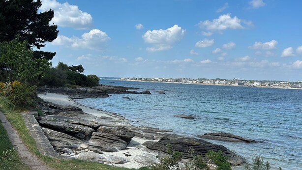 A coastal path with rocky terrain and a clear view of the sea and distant buildings. - Les Lutins - Family home - Private beach access (Concarneau)