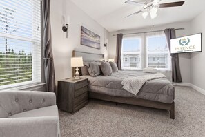 Ein Schlafzimmer mit Bett, Nachttisch, Lampe und Blick ins Freie.