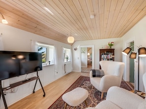 A spacious living room with a wooden ceiling, a flat-screen TV, a large armchair, a side table, and a floor lamp. - "Petteri" - 600m to the fjord by Interhome (Tim)