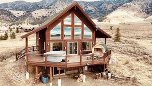 A wooden cabin with a balcony, large windows, and a fireplace.