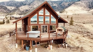 A wooden cabin with a balcony, large windows, and a fireplace. - Lake-View 5BR Cabin mins to Yellowstone - Hot Tub - Sauna - Pool Table (Island Park)