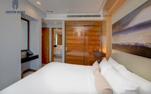 A hotel room with a large bed, a wooden wardrobe, a painting on the wall, and a desk with a lamp. - Premium 1BR living |Comfort & Class + City Center (Dubai)