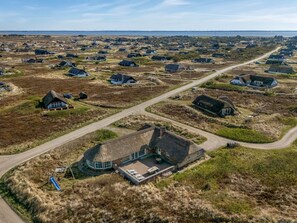 Een landelijk gebied met rieten huizen, een centraal gebouw met een ronde binnenplaats en een weg.