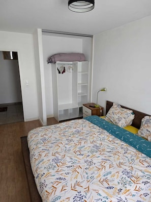 Ein Schlafzimmer mit Bett, Kleiderschrank, Nachttisch und Lampe.
