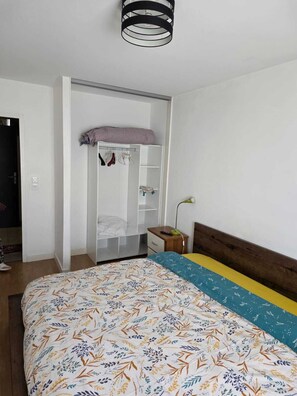 Un dormitorio con cama, armario, mesita de noche y lámpara.