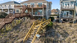 A beachfront property with wooden staircases leading to multiple levels, a private entrance sign, and a sandy path. - Salt Life | Deck Views + Steps to Beach, Sleeps 10 (North Topsail Beach)