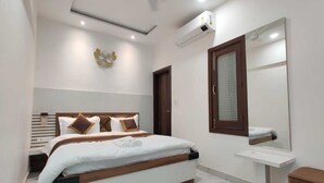 Un dormitorio moderno con cama, mesita de noche, espejo y aire acondicionado.