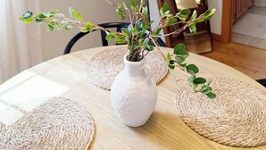A dining table with a woven placemat, a white vase with a plant, and a woven pendant light fixture. - Farmington gem near UConn Health with garage • Fast Wi-Fi • Dog Friendly (Farmington)