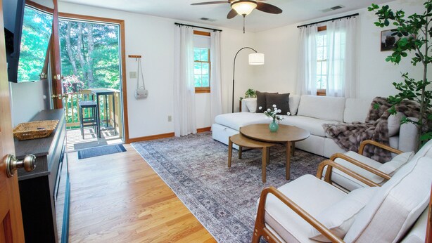 A living room with a ceiling fan, a sofa, a coffee table, and a view of a deck. - Farmington gem near UConn Health with garage • Fast Wi-Fi • Dog Friendly (Farmington)