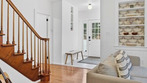 A staircase with wooden balusters, a bench, a cushioned seating area, and a shelving unit with decorative items. - Charming & Peaceful Catskills Getaway 2hr from NYC (Mountain Dale)