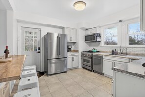 Una cocina moderna con electrodomésticos de acero inoxidable, armarios blancos y un ventanal grande.