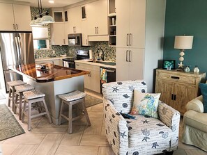 Una cocina moderna con una isla central, taburetes de bar y un sofá de estilo náutico.