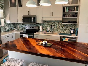 A kitchen with white cabinets, a wooden island, a microwave, and a sink. - Spectacular views with one of the best locations on Pensacola Beach (Pensacola Beach)