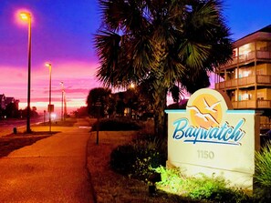 Señal de Baywatch en el número 1150, con una palmera y farolas al frente.