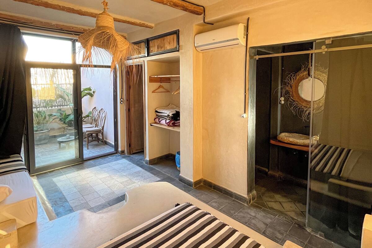 Een moderne slaapkamer met een groot bed, een hanglamp, een schuifdeur met glas en een inbouwkast.