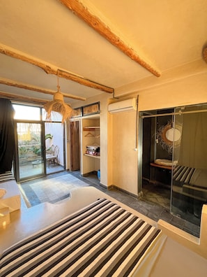 A modern bedroom with a large bed, a hanging light fixture, a sliding glass door, and a built-in wardrobe.