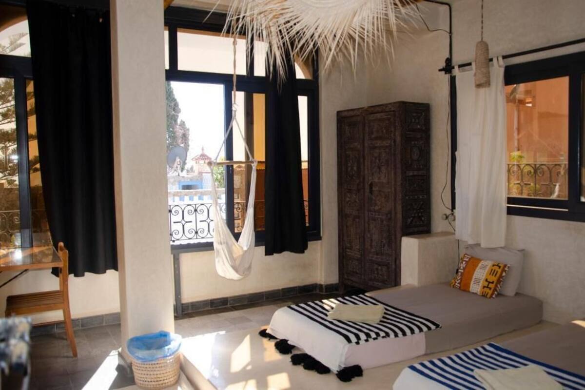 Een kamer met een bed, een raam met gordijnen, een houten kast en een hanglamp.