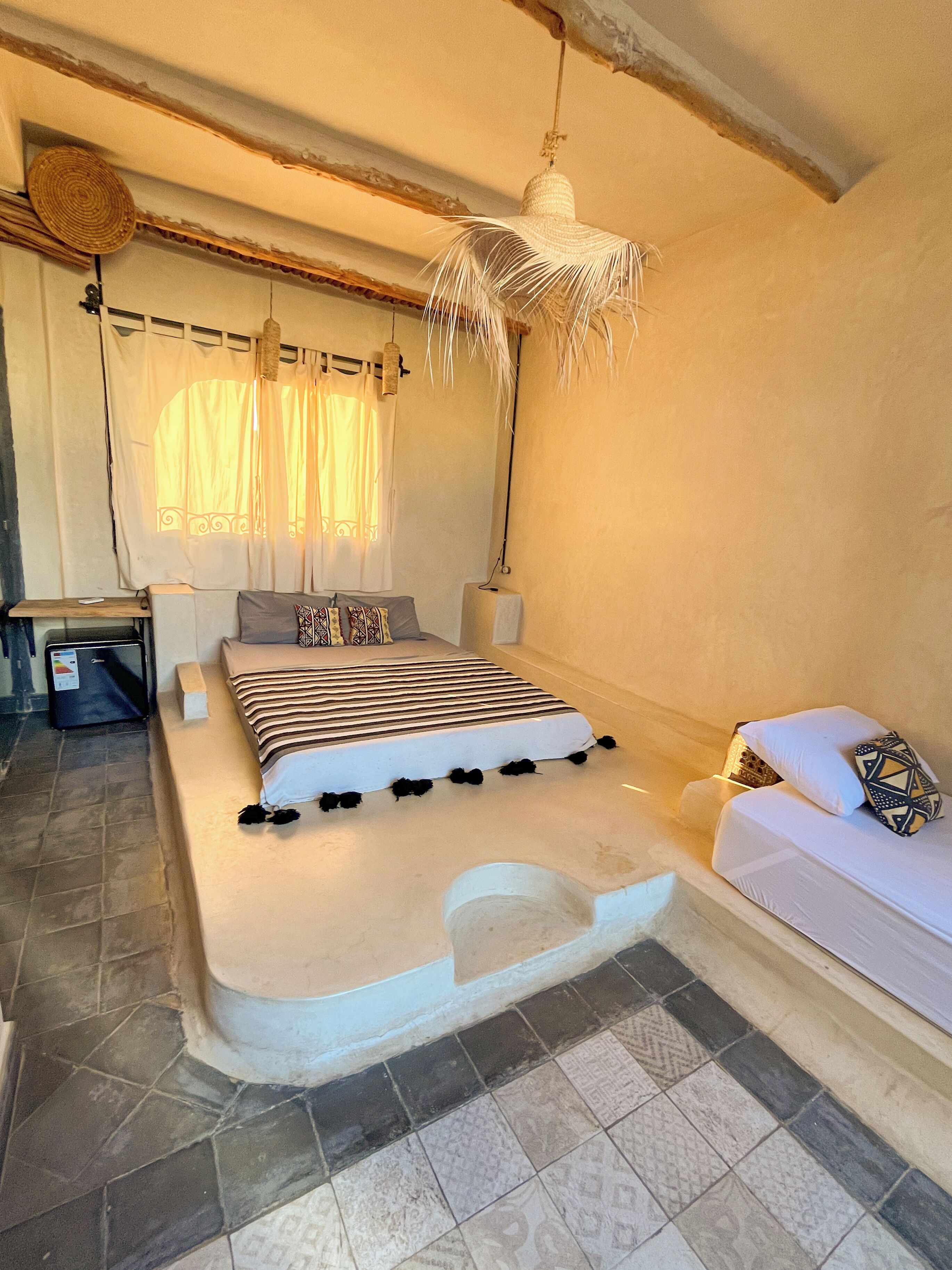 A bedroom with a bed, bedside table, and a hanging light fixture.