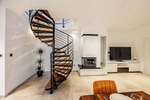 Ein modernes Wohnzimmer mit Wendeltreppe, Flachbildfernseher und Essbereich.
